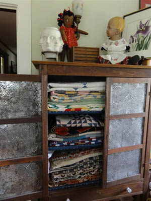 antique pie cupboard full of vintage quilts